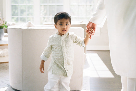 Child holding hands with an adult in a bright, minimalistic room.